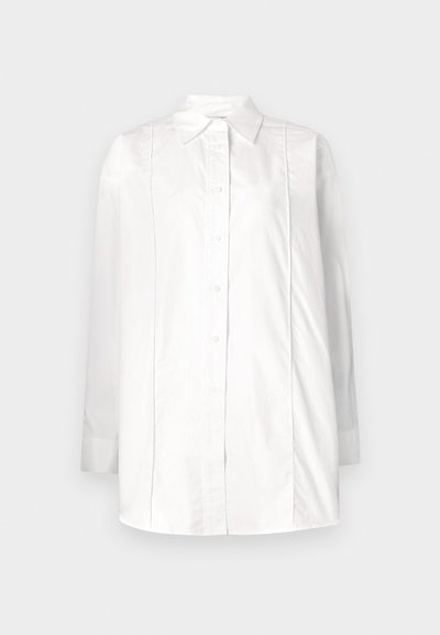 Camicia bianca a maniche lunghe in cotone con colletto classico, chiusura frontale con bottoni e dettagli a pieghe verticali sul corpino.