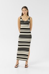 Robe maxi sans manches noire et crème à rayures, avec un design ajusté, une fente sur le côté et un logo de la marque au niveau de la poitrine. Texture côtelée lisse.