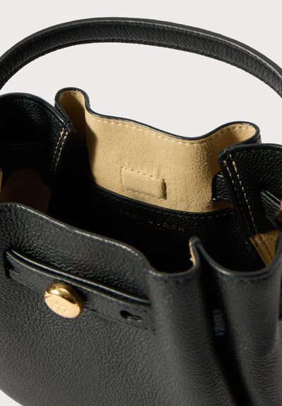 Czarna torebka typu bucket z teksturowanej skóry, z zapięciem na złoty guzik i beżową szwyrem wyściółką, przedstawiona z perspektywy otwartego wierzchu.