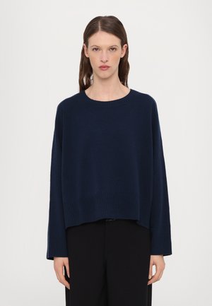 Pullover en maille bleu marine avec un col rond, des épaules tombantes et un ourlet côtelé. Le tissu semble doux et offre une coupe décontractée.