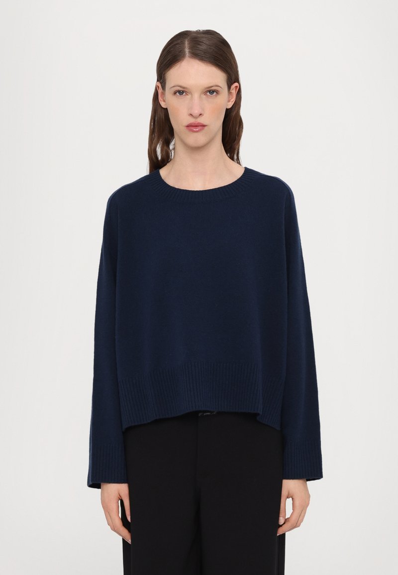 Navy blue knitted sweater with a crew neckline, dropped shoulders, and ribbed hem. The fabric appears soft and has a relaxed fit.