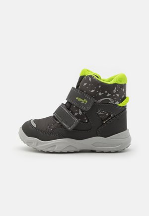 Schwarze und graue Knöchelstiefel mit Limettengrün-Akzenten, strukturiertem Obermaterial, zwei Klettverschlüssen und einem gemusterten Design mit Sternen und Planeten. Gummisohle.