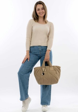 Quilted beige bag with two sturdy handles, displaying a pocket accent, paired with light blue wide-leg jeans and a beige ribbed sweater.