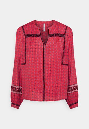 Czerwona bluzka z długim rękawem w mały kwiatowy wzór, z czarnym geometrycznym wykończeniem na piersi, rękawach i przednim rozcięciu oraz z okrągłym dekoltem.