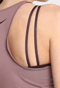 Hellblaues Sport-Top mit Rundrücken, zwei dünnen dunklen Trägern und einer glatten Stofftextur.