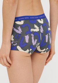 Σορτς μποξέρ Björk Borg σε σκούρο γκρι, με αφηρημένα μοτίβα από μωβ και μπλε πινελιές. Λάστιχο στη μέση σε μπλε χρώμα με το όνομα της μάρκας.