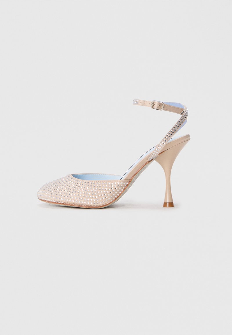 Chaussure à talons hauts beige avec un bout ouvert, ornée de strass transparents et d'une sangle à boucle. Talon aiguille avec une finition texturée.