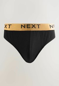 Svarta bomullstrumpor med en mjuk textur, med ett kontrasterande guld elastiskt midjeband där "NEXT" är tryckt i svarta bokstäver.