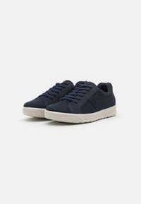 Granatowe zamszowe sneakersy z beżową gumową podeszwą, okrągłym noskiem i podwyższonymi bocznymi panelami. Posiada ciemne sznurowadła i akcenty w kolorze nici.