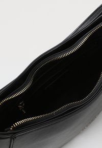 Bolso de mano de cuero negro con una textura suave, que presenta un cierre dorado y múltiples compartimentos en el interior. Diseño elegante, sin patrones visibles.