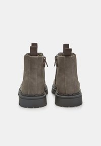 Stivali alla caviglia in suede grigio con una robusta suola in gomma nera, cuciture verticali e doppi zip laterali per una facile indossabilità. Inclusi i ganci.