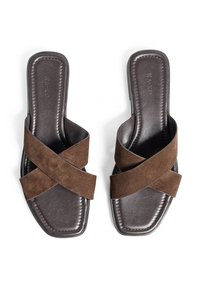 Een paar donkerbruine leren sandalen met brede bruine suede crisscrossbanden en een vierkante neus op een witte achtergrond.