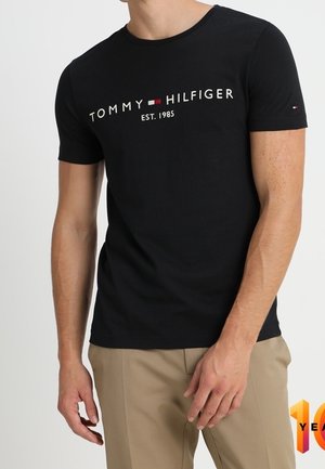 Czarny bawełniany t-shirt z krótkim rękawem, z białym logo "TOMMY HILFIGER EST. 1985" na przodzie, o gładkiej fakturze.