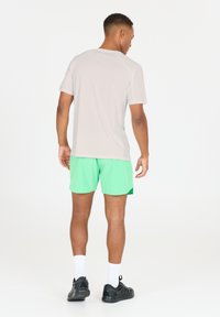 Lys grå trænings T-shirt med korte ærmer, parret med lysegrønne shorts. Model iført sorte sneakers og hvide sokker.