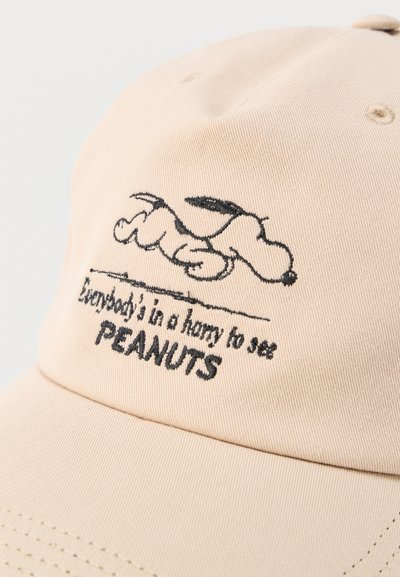 Casquette beige avec un contour noir brodé de Snoopy allongé et texte "Tout le monde est pressé de voir PEANUTS".