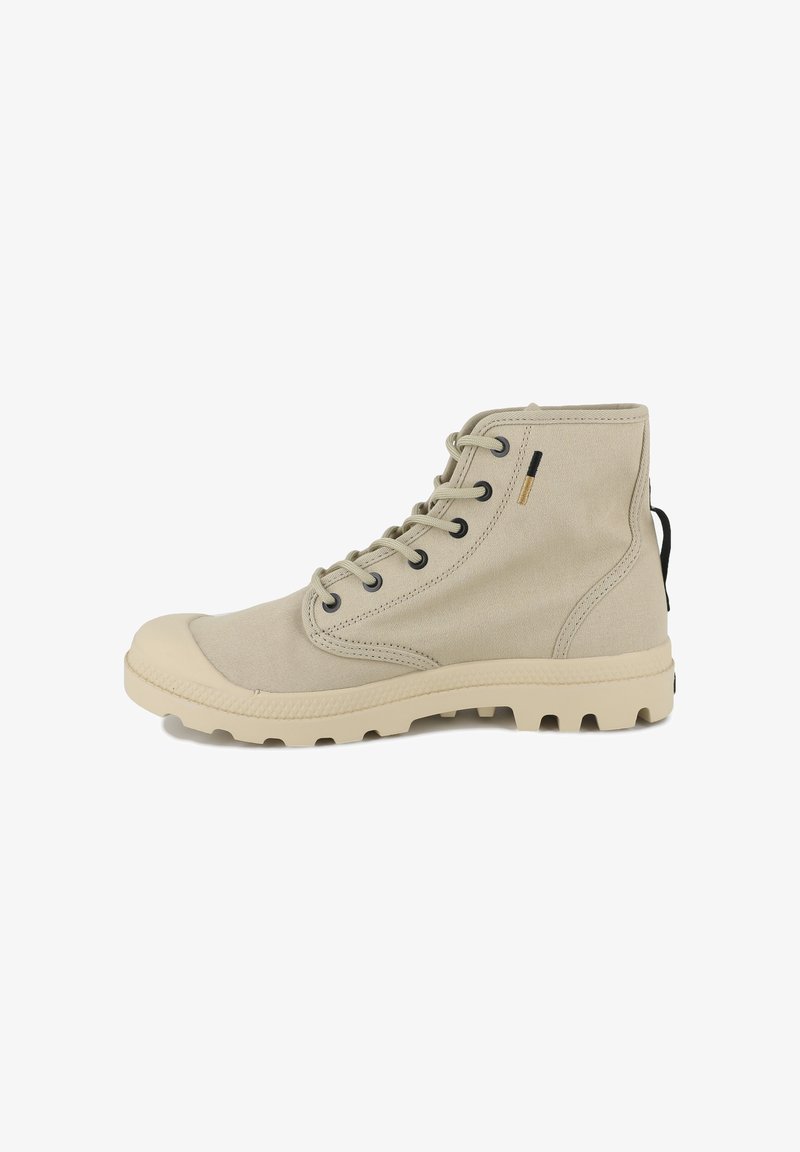 Bottes chevilles beiges avec une tige en toile, un embout en caoutchouc et une semelle texturée. Elles présentent un laçage sur le devant et une languette de tirage au talon.