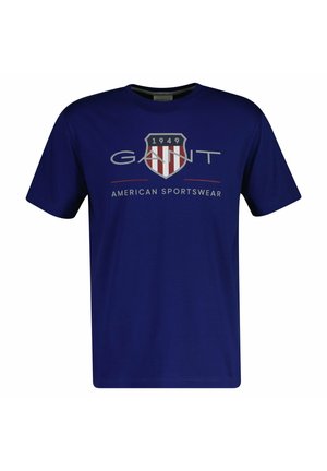 T-shirt bleu marine à manches courtes avec logo "GANT", emblème en forme de bouclier avec 1949, et texte "American Sportswear" à l'avant.