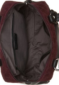 Bordeaux quiltet håndtaske med en grå stofindvending, der har flere lommer og en lynlåslukning for sikker opbevaring.