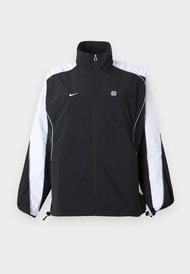 Zwart-witte Nike sportjas met volledige ritssluiting aan de voorkant, hoge kraag, en logo op de linkerborst en strepen op de mouwen.