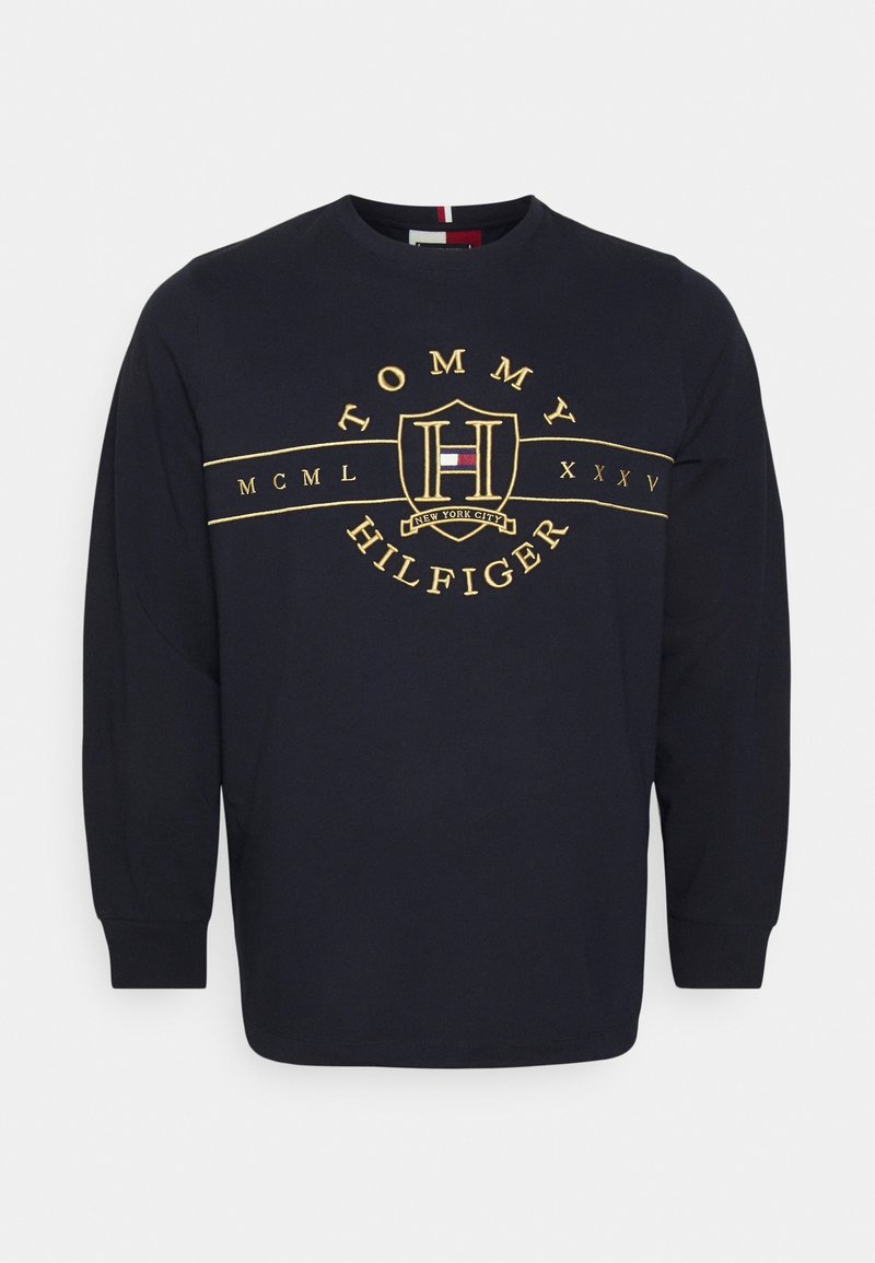 Chemise bleu marine à manches longues avec écusson et texte brodés jaunes Tommy Hilfiger, comportant des chiffres romains et une bannière "New York City".