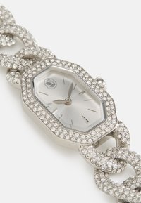 Orologio ottagonale argento con una lunetta tempestata di cristalli e un bracciale a catena, caratterizzato da un quadrante minimalista con lancette e indicatori argentati.