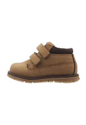 Brun småbarnssko med to justerbare stropper med velcro, polstret krave, tekstureret sål og afrundet tå mod hvid baggrund.