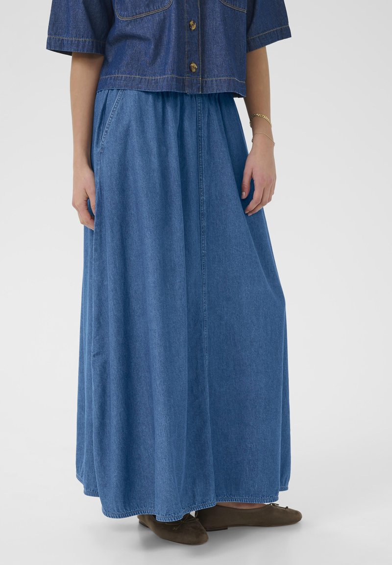 Jupe maxi en denim de couleur bleu clair, dotée d'une taille élastique et d'un design fluide. Texture lisse et coupe longueur cheville.