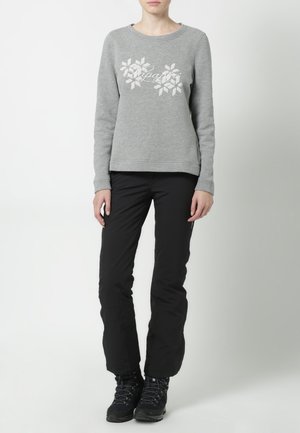 Sweat-shirt gris avec motif flocon de neige blanc et texte, associé à un pantalon noir et des bottes de randonnée noires. Design simple et décontracté.