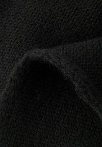 Czarny dzianinowy materiał o miękkiej, teksturowanej powierzchni. Materiał wydaje się puszysty i jest ściśle utkany, z niewielkimi różnicami w grubości.