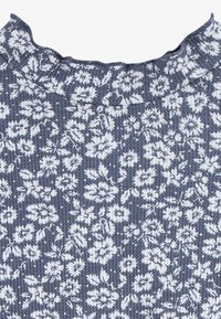 Tela con estampado floral en azul marino y blanco, con una superficie texturada y un escote con volantes. Motivos florales pequeños a lo largo.