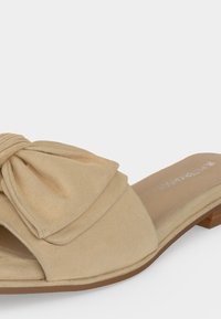 Sandale beige à bout ouvert avec un grand nœud en tissu noué à l’avant et un petit talon bloc en bois.