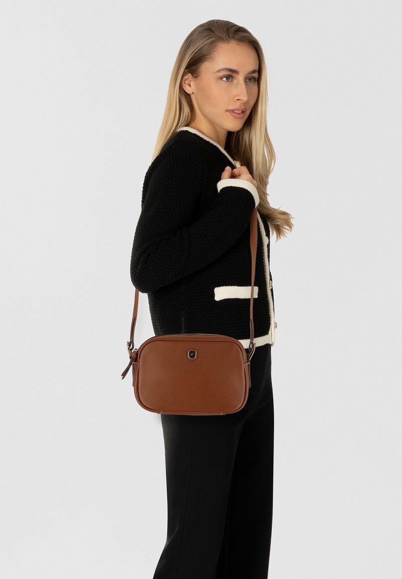 Braune Leder-Crossbody-Tasche mit einer strukturierten Oberfläche, rechteckiger Form und einem kurzen verstellbaren Trageriemen. Dezentes Logo-Detail auf der Vorderseite.