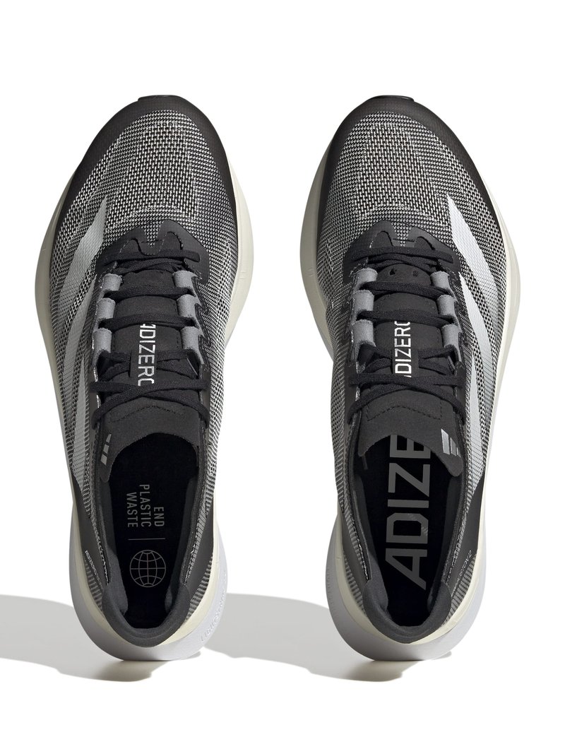 Des chaussures de sport noires et grises avec un dessus en maille, présentant un motif texturé, des accents blancs et une semelle de couleur claire.