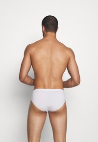 Weiße Baumwollunterhosen auf einer männlichen Figur präsentiert, die eine glatte Textur und eine enge Passform zeigen, mit einem schlichten Design und ohne sichtbare Muster.