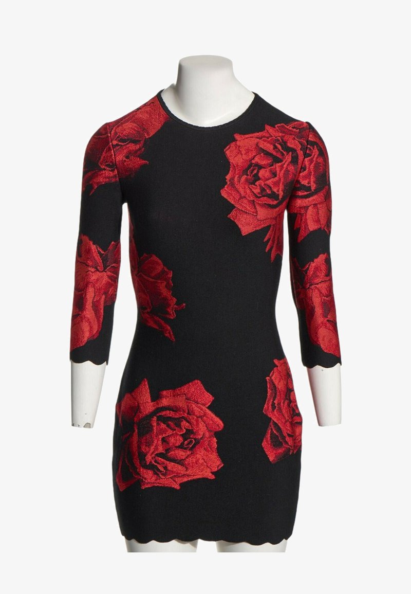 Robe noire cintrée avec de grands motifs de roses rouges et des manches trois-quarts, affichée sur un buste de mannequin blanc.