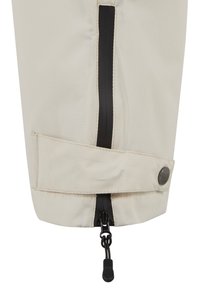 Polsino di giacca impermeabile beige con zip nera, chiusura a bottoni e cordino. Presenta una texture liscia e cuciture visibili.