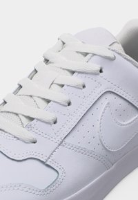 Λευκό αθλητικό παπούτσι με υφασμένες κορδόνια, διάτρητη πλευρική επιφάνεια και ανάγλυφο λογότυπο swoosh σε λείο δέρμα στην επάνω επιφάνεια.