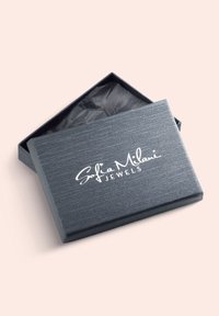 Grå smyckesask med en texturerad yta, öppen för att avslöja svart silkespapper inuti. "Sofia Milani JEWELS" i vit kursiv på toppen.