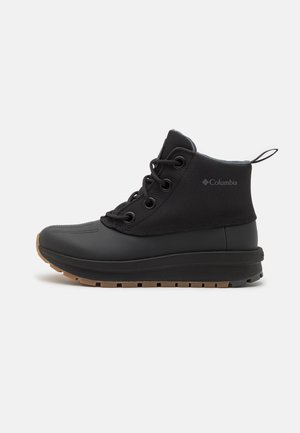 Botte noire mi-hauteur imperméable avec fermeture à lacets sur le devant, semelle en caoutchouc texturée, tige en tissu, languette et logo Columbia sur le côté.