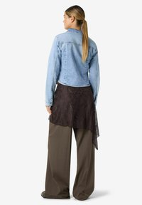 Teksariidest jakk, helesinine; must pitsist ülekattega seelik; laia säärega pruunid püksid. Tagantvaade näitab kihtides kangaid ja lõdvestunud istuvust.