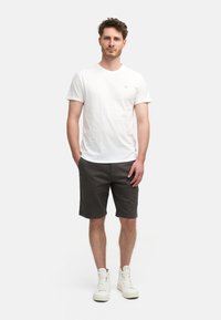 Camiseta blanca con mangas enrolladas, pantalones cortos grises y zapatillas altas blancas; ajuste casual, tejido de algodón suave, diseño minimalista.