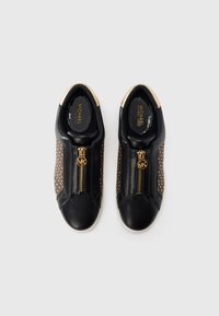 Baskets en cuir noir avec un détail de fermeture éclair dorée, agrémentées de clous de couleur bronze sur les côtés et d'un talon brillant doré.