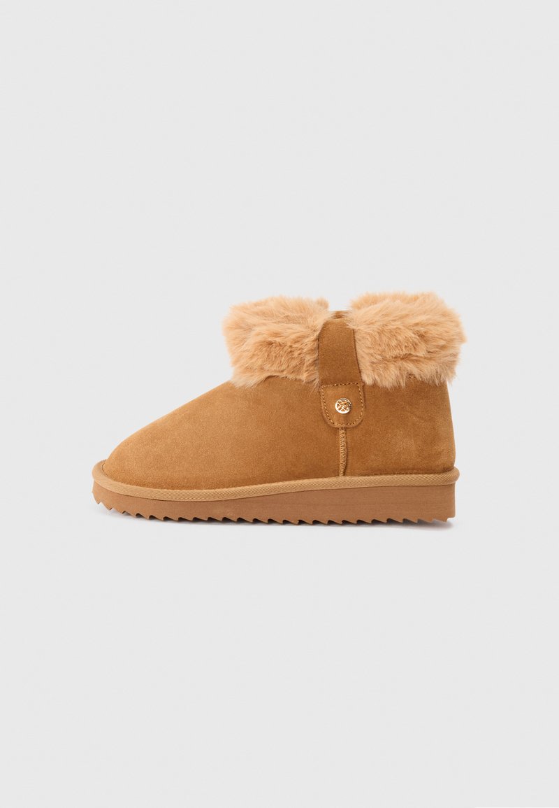 Chestnut brown suede ankle boot with plush fur cuff, flat ridged sole, and decorative button detail on side.