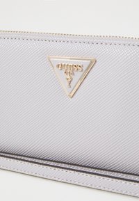 Portafoglio grigio con texture, dotato di una placca in plastica a forma triangolare. Presenta una cerniera dorata e cuciture eleganti lungo il bordo.