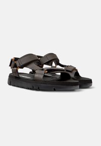 Sandalias negras con correas ajustables y acentos marrones. Plantilla acolchada con una superficie texturizada y suela de goma para mayor agarre.