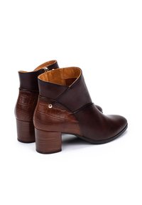 Bottines en cuir marron foncé avec un motif de crocodile texturé au niveau du talon, bout rond et un petit talon carré ; l'intérieur est doublé de tan.