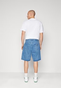 Denim shorts in light blue, featuring a relaxed fit, back pockets, and a sewn label on the right pocket. Pairing with a white t-shirt.