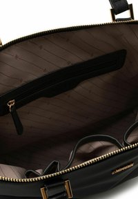 Borsa nera con apertura con zip, dotata di una fodera interna liscia con un motivo sottile, una tasca interna con zip e accessori in oro.