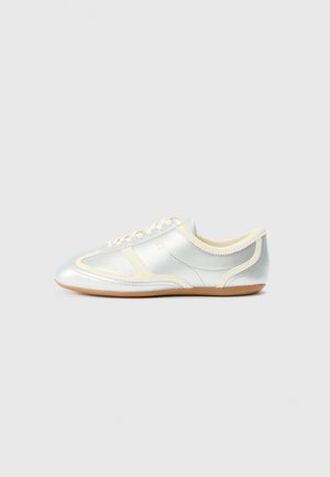 Silver synthetic sneakers with cream accents, low profile, rounded toe, and flat rubber sole; features classic stitching and lace closure.