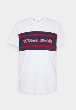 Valkoinen puuvillapaita, jossa on tummansiniset vaakaraitat. Rintakehässä punaisella kirjoitettu "TOMMY JEANS". Lyhyet hihat, pyöreä pääntie.